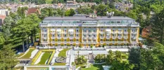 The grand exterior of Palace Merano, with its multiple storeys, gold-yellow walls and landscaped grounds