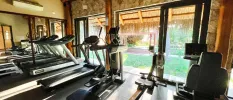 Treadmills and rowing machine in a gym with stone walls