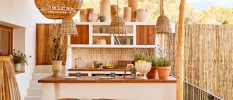 Boho-style open-air corner with hanging rattan lanterns, a wooden desk with potted plants and surrounding wooden fencing