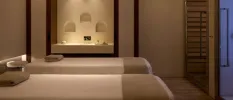 Neutral treatment cabin with two massage beds, a marble vanity unit and soft lighting
