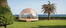 Transparent dome for yoga in a sunny lawned garden with ocean views