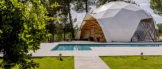 Outdoor garden with a swimming pool with a domed structure with clear windows and a white covering