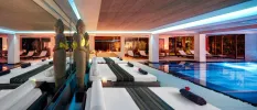 Indoor pool surrounded by white daybeds, Buddha statues and LED ceiling lights
