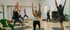 Group participating in a class with mats stretching their arms up in their air