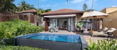 Villa with doors open to a swimming pool and terrace with loungers and umbrellas, potted plants and a table and chairs