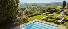Steps into a swimming pool in a lawned terrace overlooking the countryside, complete with white loungers and parasols