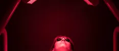 Woman lies under red infrared light with protective glasses on  