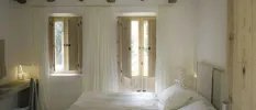 Bedroom with wooden beams, white walls and white bedding 
