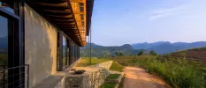 Wooden and stone building overlooking mountains and tropical greenery under a blue sky