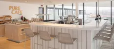 Airy rooftop restaurant with a central white bar, wooden buffet stations and a sign on the wall that reads 'Pure Cafe'