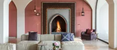 Lounge area with an Ottoman-style arched fireplace, blush walls and a cream sofa