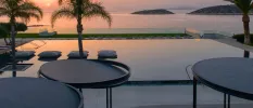 Pool terrace at sunset, with an ocean view, infinity edge and surrounding of palm trees