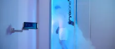 Man in white shorts in a blue-lit cryotherapy chamber 