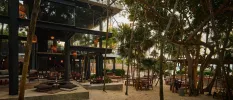 Three-storey wooden building with outdoor tables and chairs in a wooded area
