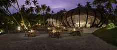 Bar with giant domed structure, overlooking the sand and tables and chairs lit by candlelight