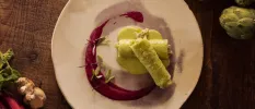 White plate with green roll-like food and a purple sauce garnish
