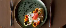 Dark grey plate with smoked salmon, asparagus, carrot coils and onion
