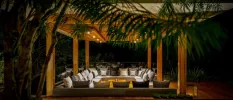 Stylish white cushioned sofa in a U-shape under a wooden pergola at night