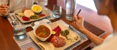 A couple eating together their lunch of different curries in an indoor restaurant