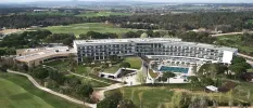 Multi-storey white hotel with pools edged by rolling countryside