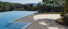 Outdoor swimming pool with steps and an infinity edge, with a view of the surrounding countryside
