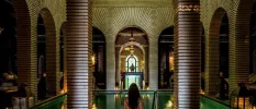 Woman standing in front of a pool in a room of pillars and sweeping archways