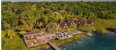 Rustic resort with wooden decking, thatched A-frame villas and a jetty jutting into turquoise waters and backed by thick jungle