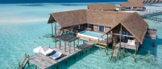 Thatched-roof overwater villas with wooden decks, private pools and steps into a clear blue lagoon