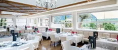Elegant restaurant with a wood-beamed ceiling, crisp white tablecloths, a chandelier and windows showcasing views of the valley and mountains
