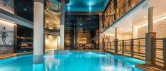Indoor swimming pool surrounded by retro black and white wall murals, stone walls and white pillars