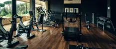 Gym with black walls, wooden floors and black equipment including treadmills, bikes and weights