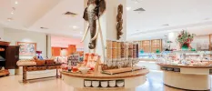 Buffet stations in a bright white restaurant, with an elephant head statue attached to a white column in the middle