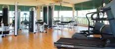 Weight machines and treadmills in a bright airy gym with floor-to-ceiling windows