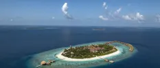 Circular Maldivian island with pure white beaches, an interior with thick greenery, turquoise shallows and wooden water villas and jetties