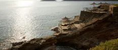Stone platforms with steps into the sea, lined with thatched parasols and cream loungers