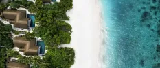 Aerial view of white sands, turquoise waters and tropical greenery, with thatched rooftops and swimming pools in between