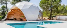 Wooden dome with a white cover next to a swimming pool among gardens