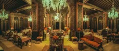Decadent room with chandeliers, patterned pillars, and terracotta sofas