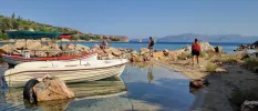 Small cove with a fishing boat, and two people admiring the surrounding sea views