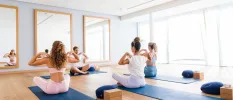 Women in active wear on mats in a fitness class in a well-lit studio 