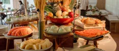 Buffet station with plates of fruit and a tray of bread rolls