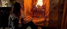 Lady reading a book in front of the fire