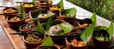 Brown bowls laid out on a table, with bamboo leafs inside topped with rice mounds, vegetables and lentils