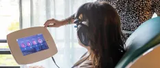 Woman sitting in a chair with a machine, choosing from options that list De-stress, Relaxation, Recovery and Focus