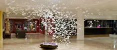 Modern art mural, with a sculpture of an open crystal on the floor, topped with hundreds of white cut outs designed to look like birds suspended from the ceiling