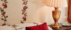 Rose-patterned headboard, red cushion and nightstand with lamp