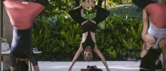 Group in yoga poses on a terrace overlooking lush greenery