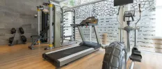 Airy gym studio with full-length windows, a treadmill, bike and weights and wooden flooring