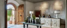 Hotel lobby with grand wooden doors, stone walls and a table filled with black candlesticks
