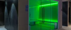 Green-lit steam room with a glass door 